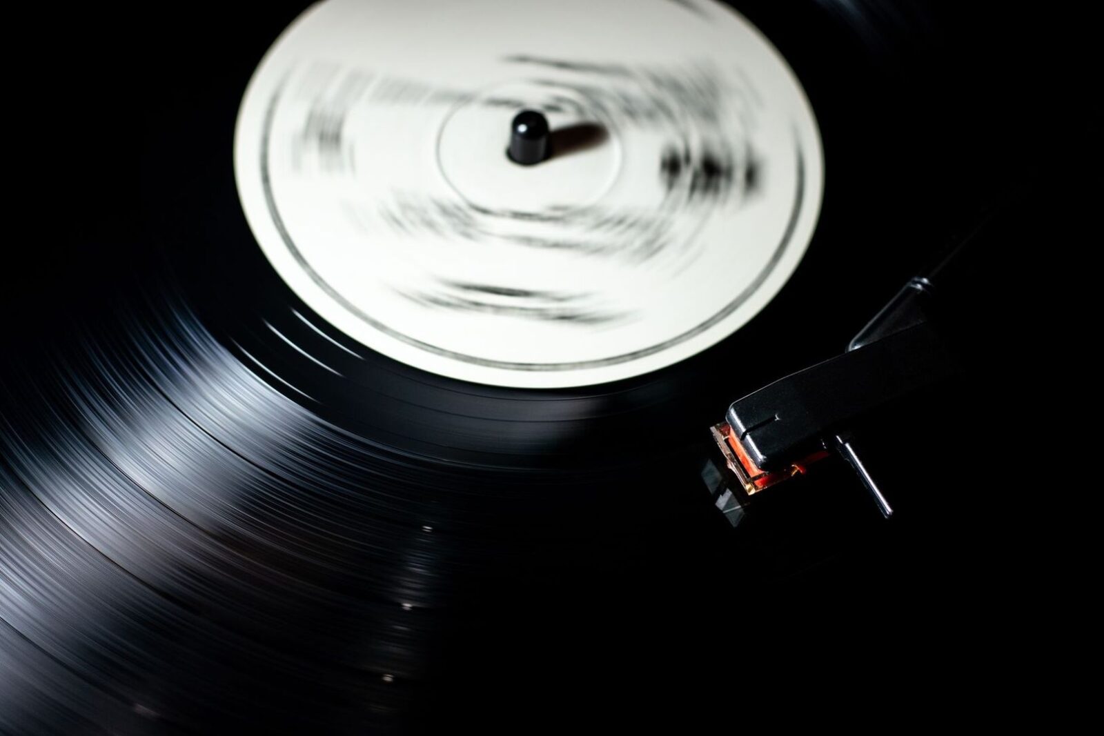 Nærbillede af en roterende vinylplade og pickup på en pladespiller