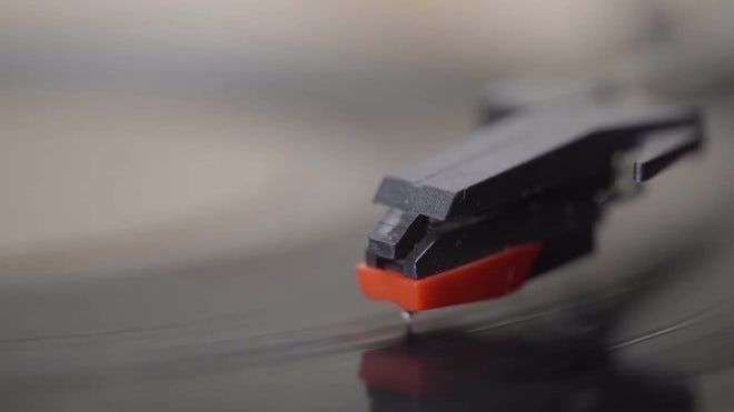 Nærbillede af en pickupnål, der følger rillen på en vinylplade
